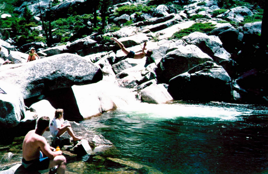 Someone diving off the rocks above Pretzel's pool at the Kegger Backpack — mid-air above the water